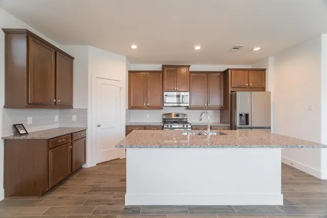a large kitchen with granite countertop a sink a stove counter space and cabinets