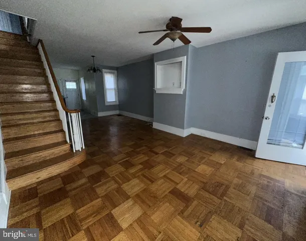 a view of an empty room with wooden floor and stairs