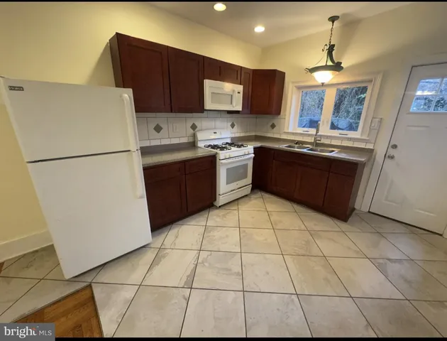 a kitchen with stainless steel appliances granite countertop a refrigerator a sink a stove a microwave and a counter