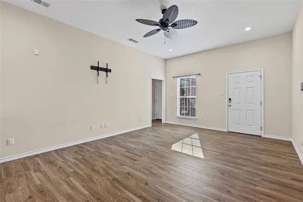 a view of an empty room with a window and wooden floor