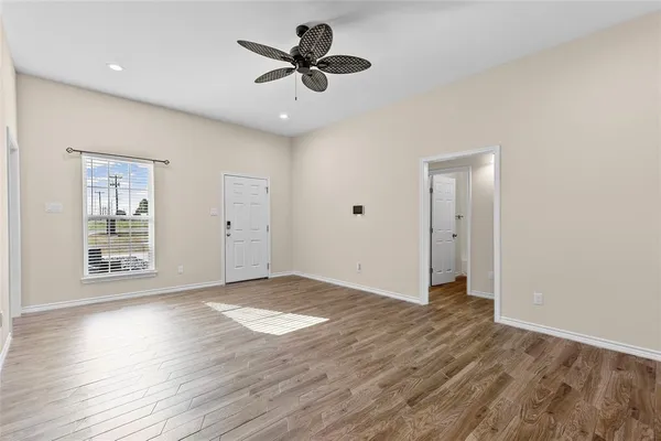 a view of an empty room with a window and wooden floor