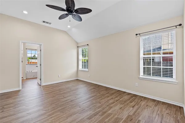 a view of an empty room with a window and wooden floor