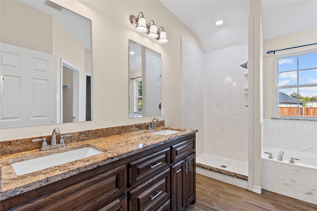 2910 Monroe Street Commerce, TX 75428 - Photo 15 of 34 a bathroom with a granite countertop sink a mirror and a bathtub