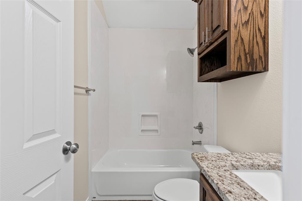2910 Monroe Street Commerce, TX 75428 - Photo 24 of 34 a bathroom with a granite countertop sink toilet and shower
