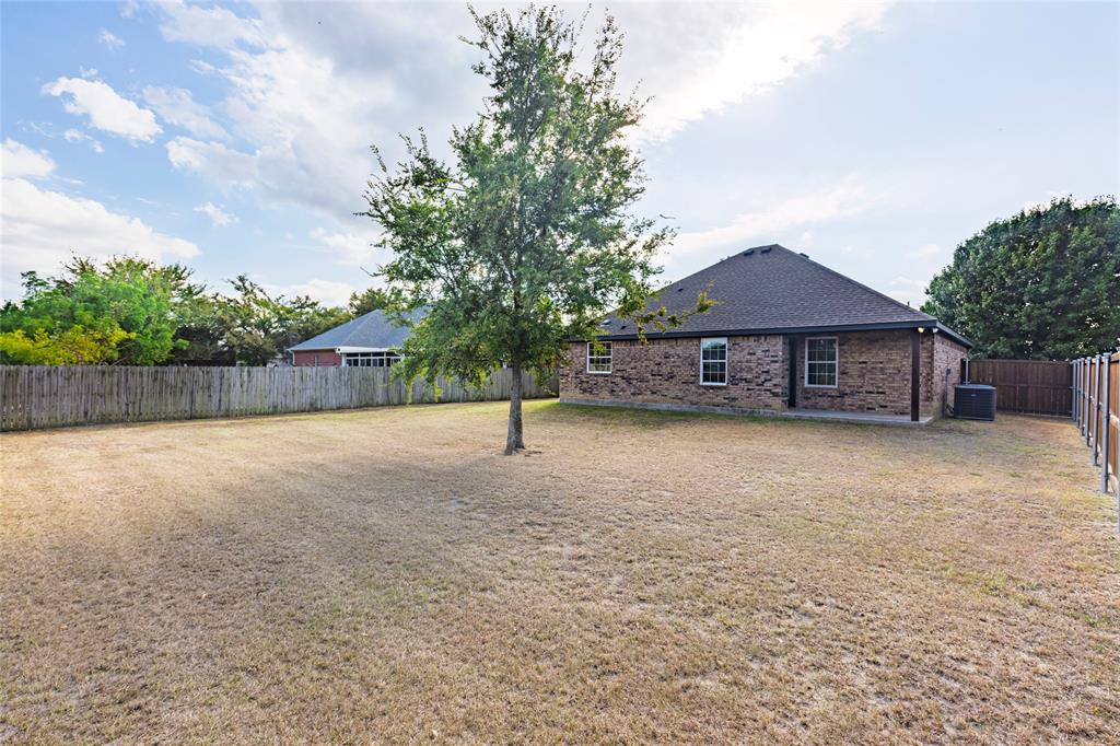 2910 Monroe Street Commerce, TX 75428 - Photo 30 of 34 a view of a house with a yard and a large tree