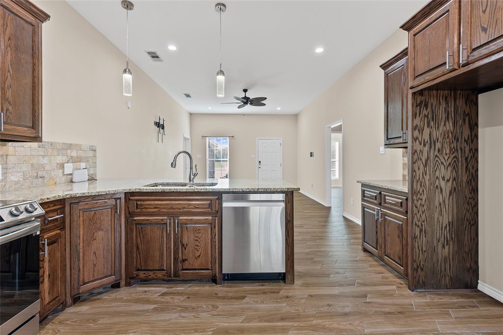 2910 Monroe Street Commerce, TX 75428 - Photo 6 of 34 a large kitchen with stainless steel appliances granite countertop a stove a sink dishwasher and a refrigerator with wooden floor