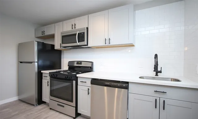 a kitchen with stainless steel appliances granite countertop white cabinets a microwave a sink and a refrigerator