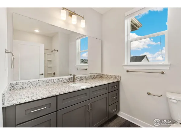 a bathroom with a granite countertop sink mirror and toilet