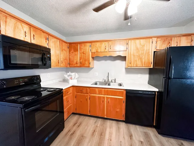 a kitchen with stainless steel appliances a stove a sink a microwave a refrigerator and cabinets