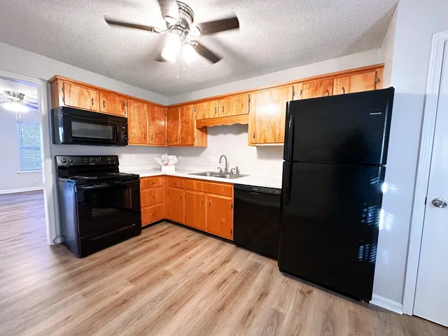 a kitchen with stainless steel appliances granite countertop a refrigerator a sink a stove a microwave and wooden floor