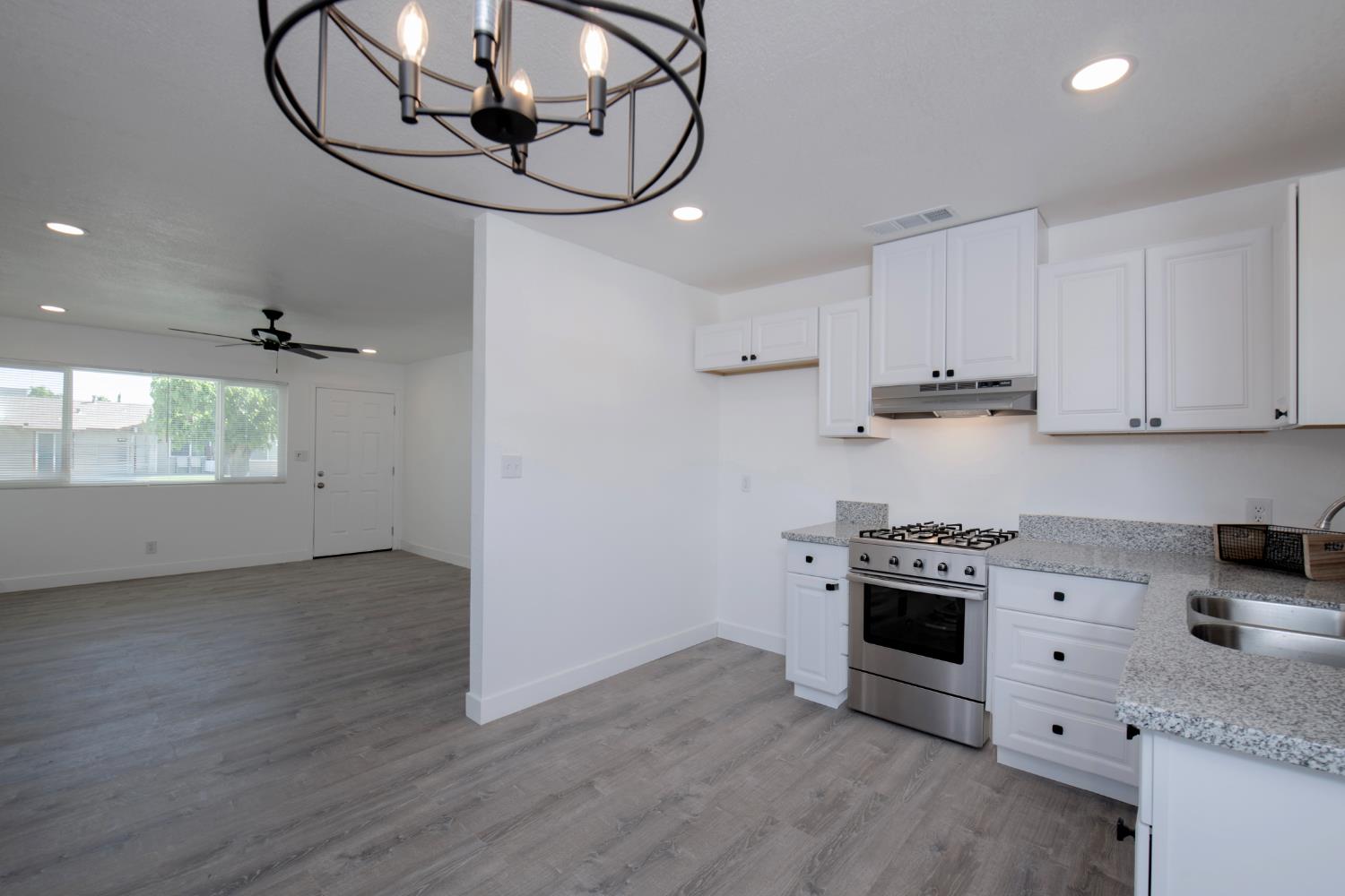 266 L Street Mendota, CA 93640 - Photo 9 of 21 a kitchen with stainless steel appliances granite countertop a stove a sink and a white cabinets with wooden floor next to windows