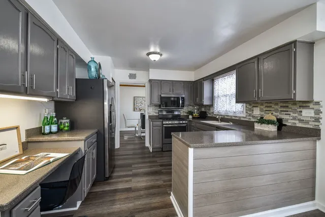 a kitchen with stainless steel appliances granite countertop a sink dishwasher stove and wooden cabinets