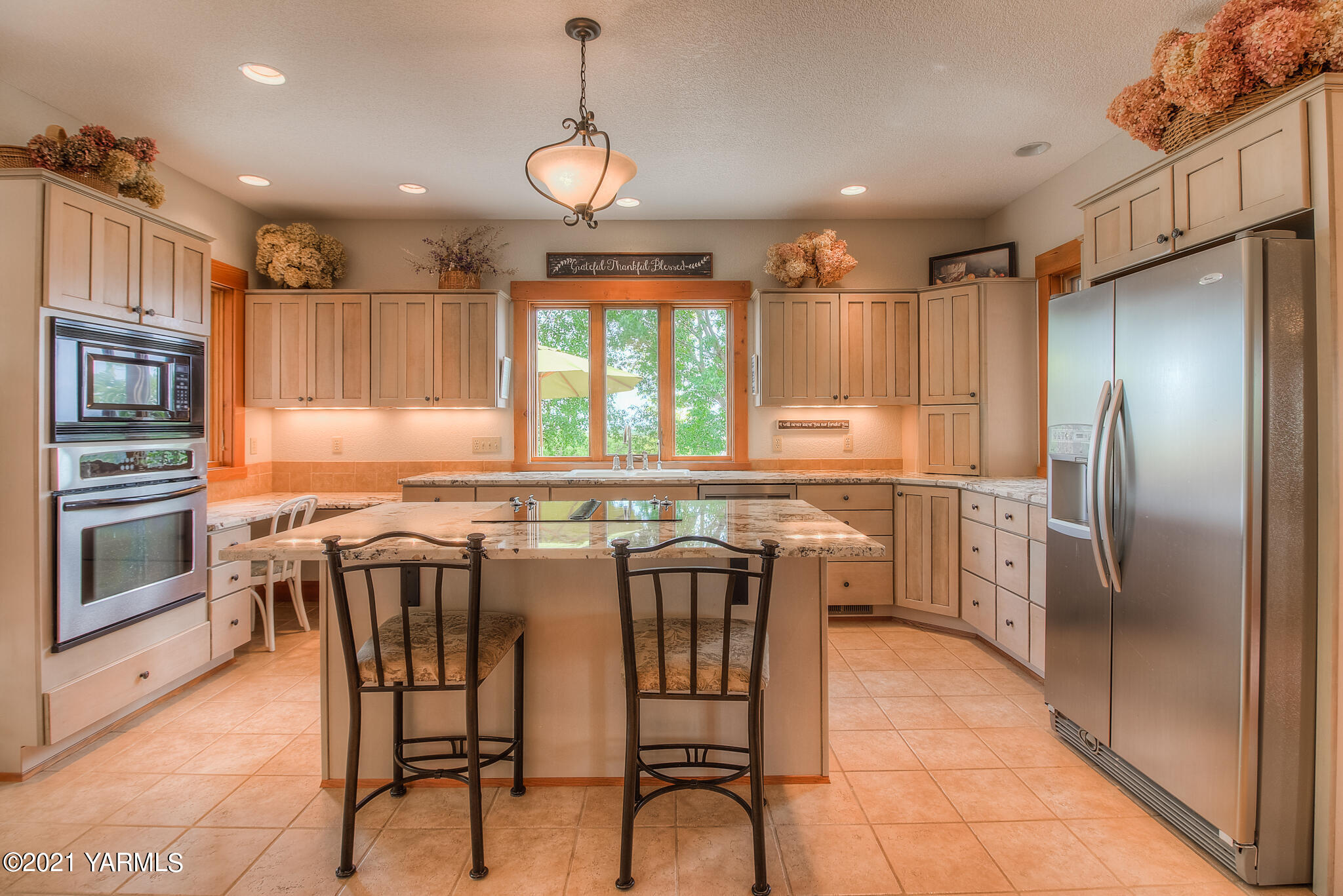 3050 Thacker Road Zillah, WA 98953 - Photo 20 of 64 a kitchen with kitchen island granite countertop a table chairs microwave and refrigerator