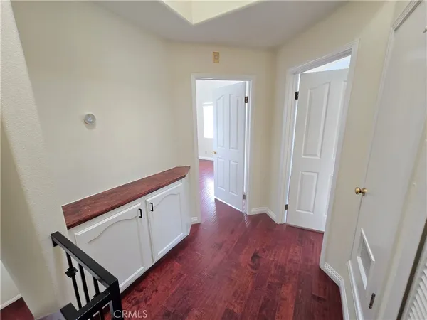a hallway with wooden floor and stairs