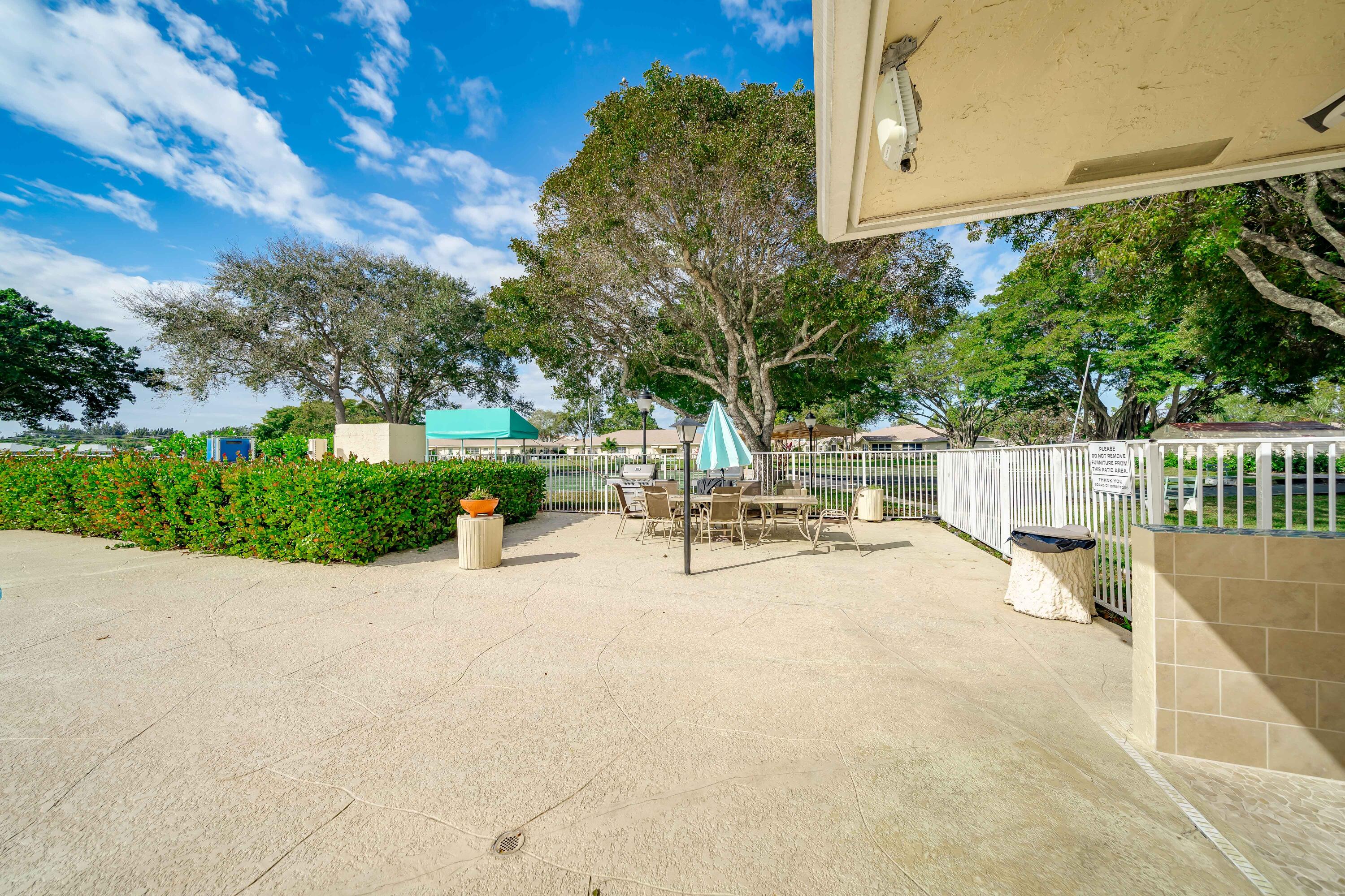 14240 Nesting Way, Unit D Delray Beach, FL 33484 - Photo 42 of 45 a view of a patio with table and chairs and potted plants