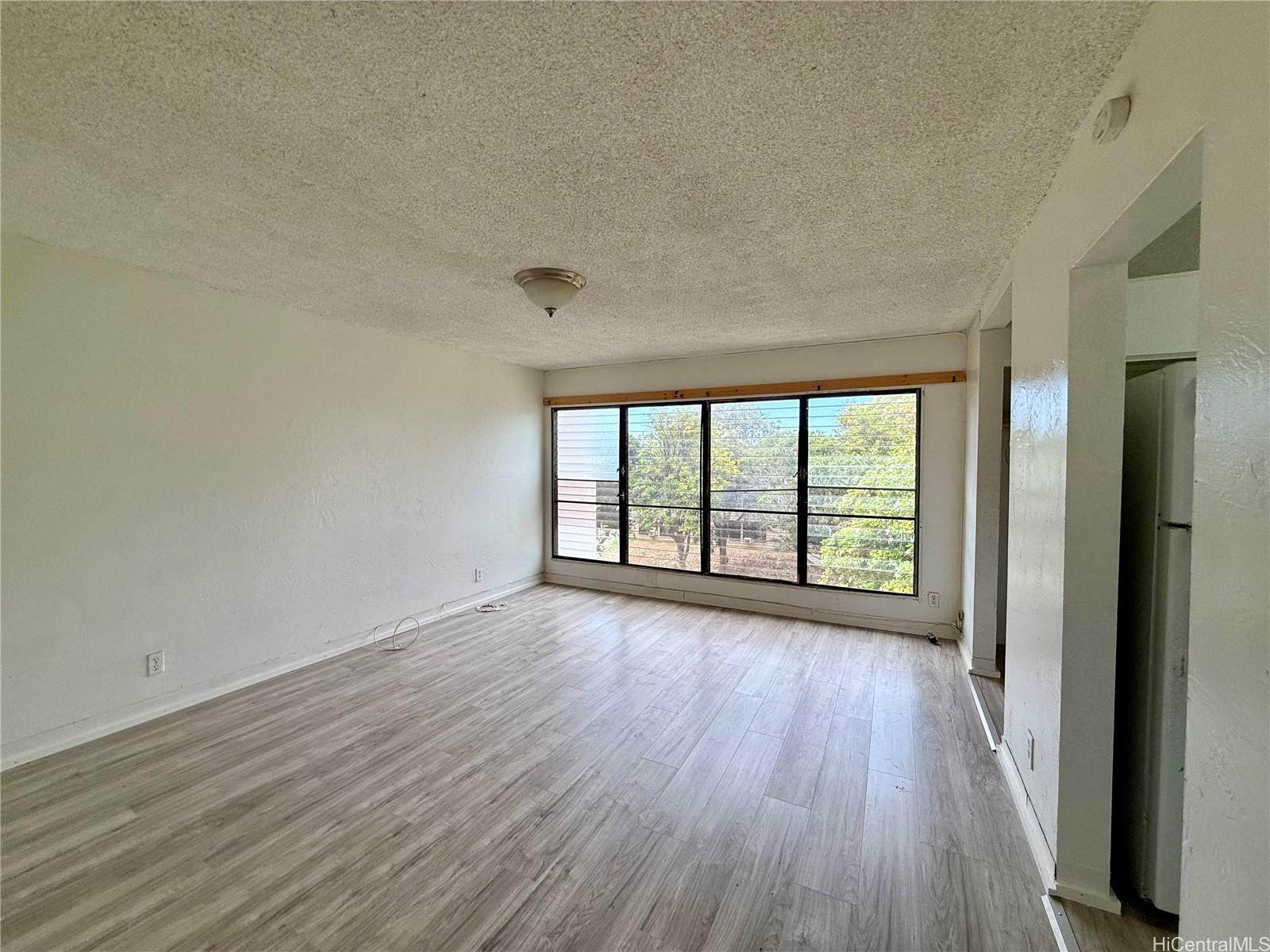 87-134 Helelua Street, Unit A302 Waianae, HI 96792 - Photo 3 of 16 wooden floor in an empty room with a window