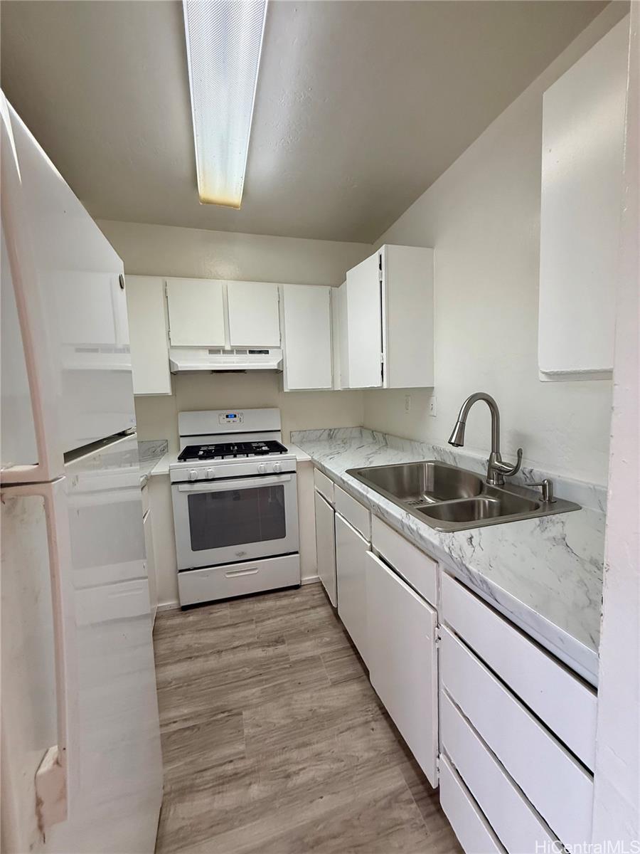 87-134 Helelua Street, Unit A302 Waianae, HI 96792 - Photo 4 of 16 a kitchen with white cabinets and appliances