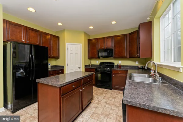 a kitchen with stainless steel appliances granite countertop a stove refrigerator and a sink