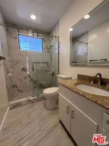 a spacious bathroom with a granite countertop sink a toilet and a shower