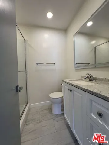 a spacious bathroom with a granite countertop sink a toilet and a shower