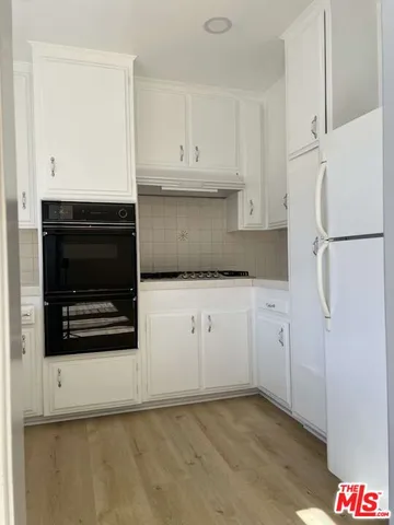 a kitchen with white cabinets and sink