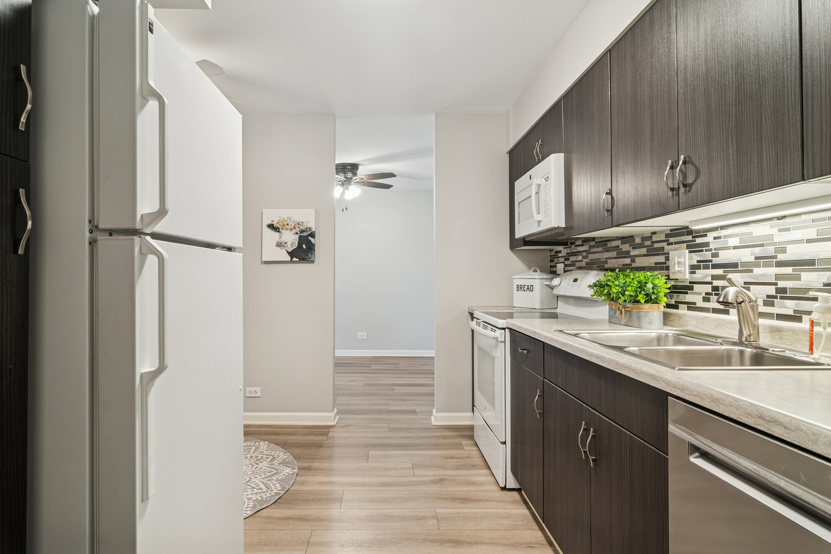 1605 East Central Road, Unit 111B Arlington Heights, IL 60005 - Photo 3 of 26 a kitchen with granite countertop a sink and wooden cabinets