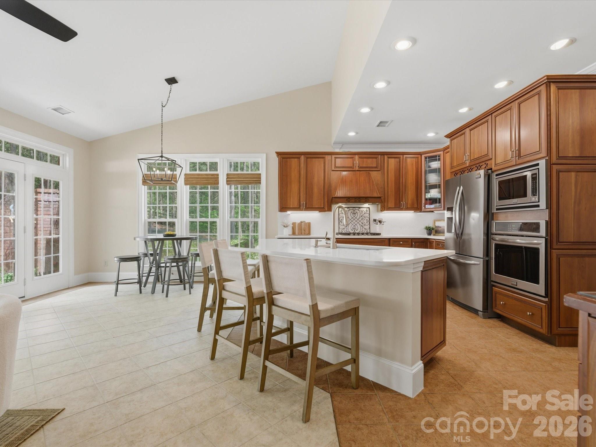 809 Savile Lane Fort Mill, SC 29715 - Photo 13 of 48 a kitchen with stainless steel appliances granite countertop a stove a refrigerator a oven a sink with a dining table and chairs