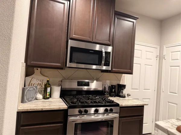 a kitchen with stainless steel appliances granite countertop a stove microwave and sink