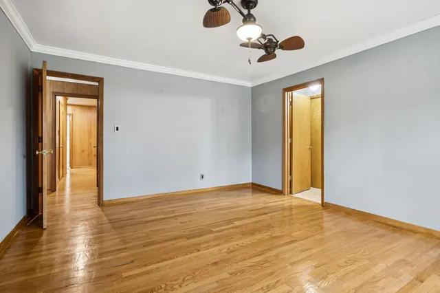 a view of a big room with wooden floor ceiling fan and windows
