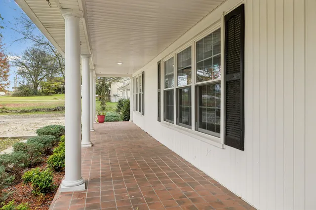 an empty room with wooden floor a ceiling fan and windows