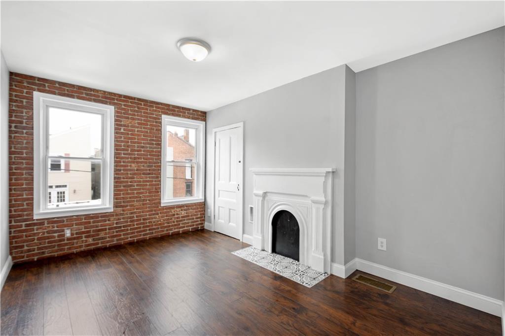 162 Locarna Way Pittsburgh, PA 15201 - Photo 18 of 25 an empty room with wooden floor windows and a fireplace