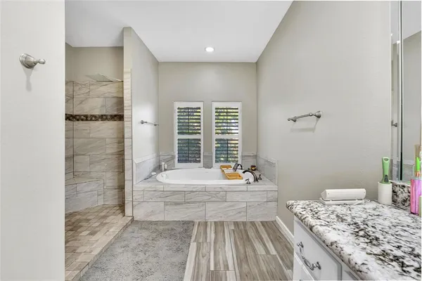 a bathroom with a granite countertop sink and a bathtub
