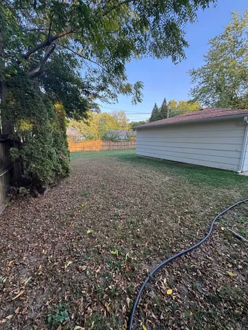 a view of a yard with wooden fence and trees