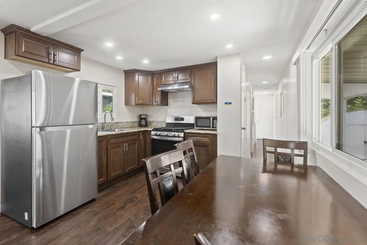 900 Howard Avenue, Unit 54 Escondido, CA 92029 - Photo 10 of 25 a kitchen with stainless steel appliances granite countertop a refrigerator a stove a sink a dining table and chairs with wooden floor