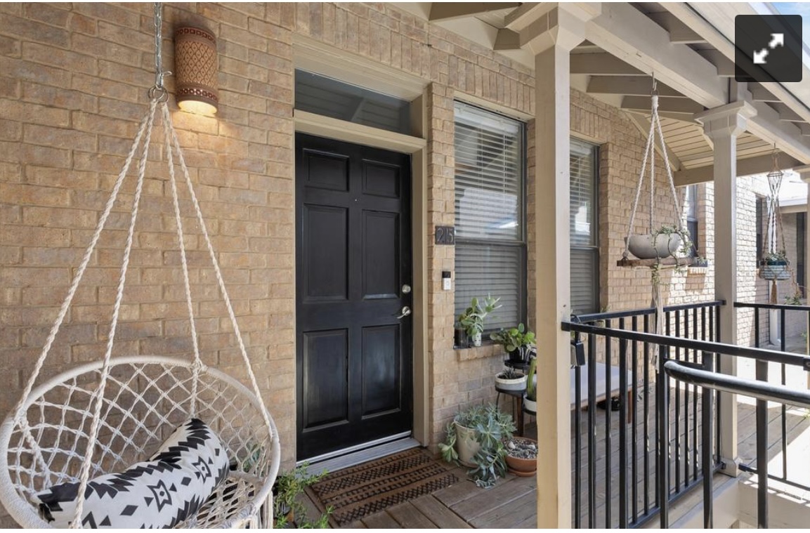 611 East 45th Street, Unit 25 Austin, TX 78751 - Photo 5 of 21 Brick facade featuring a panel door with transom window, covered porch with wood-finish flooring, and black metal railings