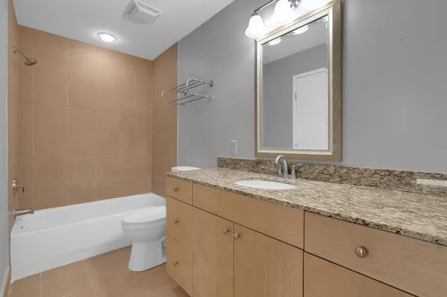a bathroom with a granite countertop sink mirror vanity and toilet