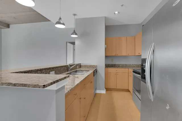 a kitchen with stainless steel appliances granite countertop a sink and a refrigerator
