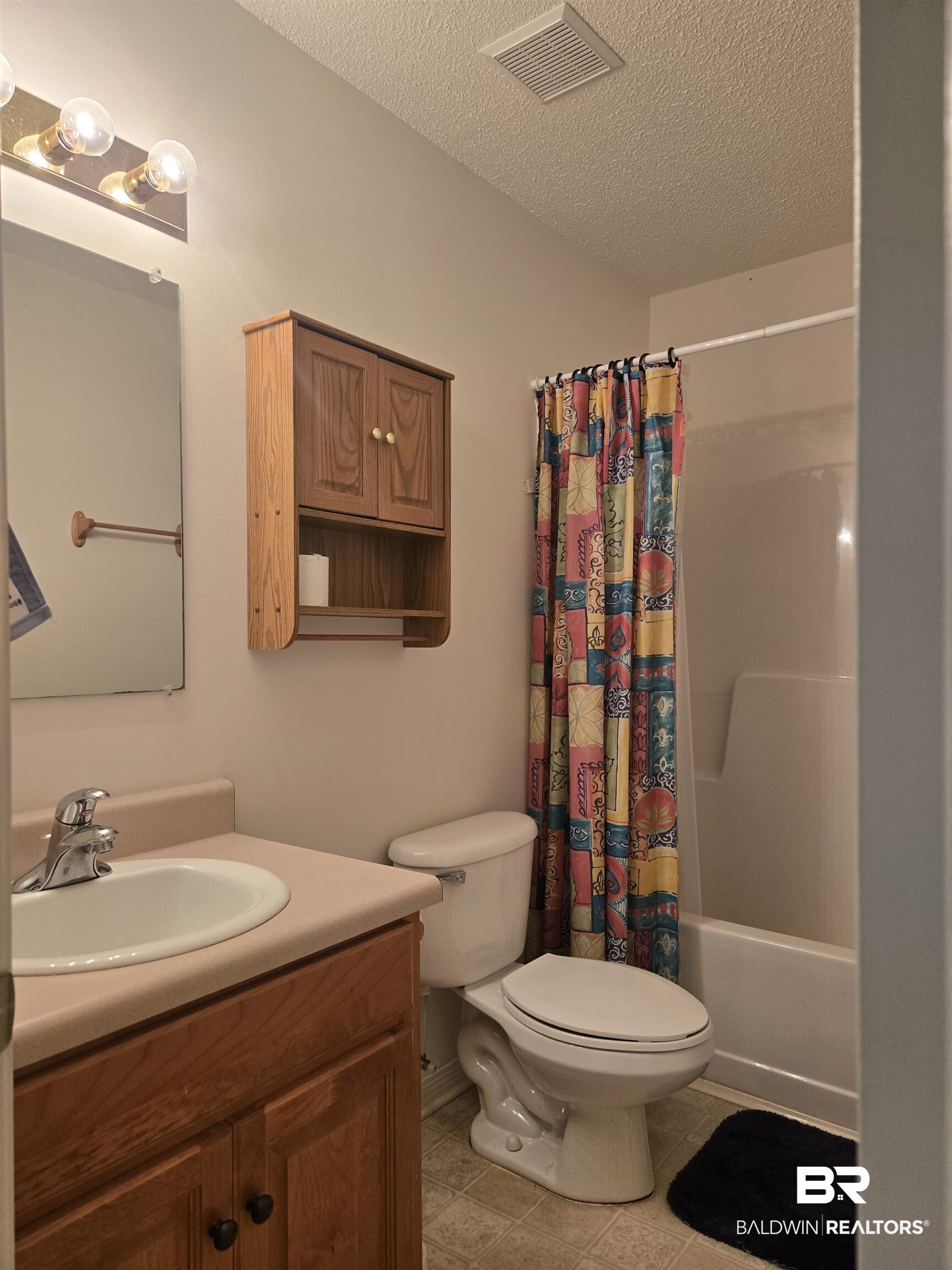 2554 Riverside Drive Mobile, AL 36605 - Photo 22 of 43 Bathroom with shower / bathtub combination with curtain, a textured ceiling, vanity, and light tile patterned flooring