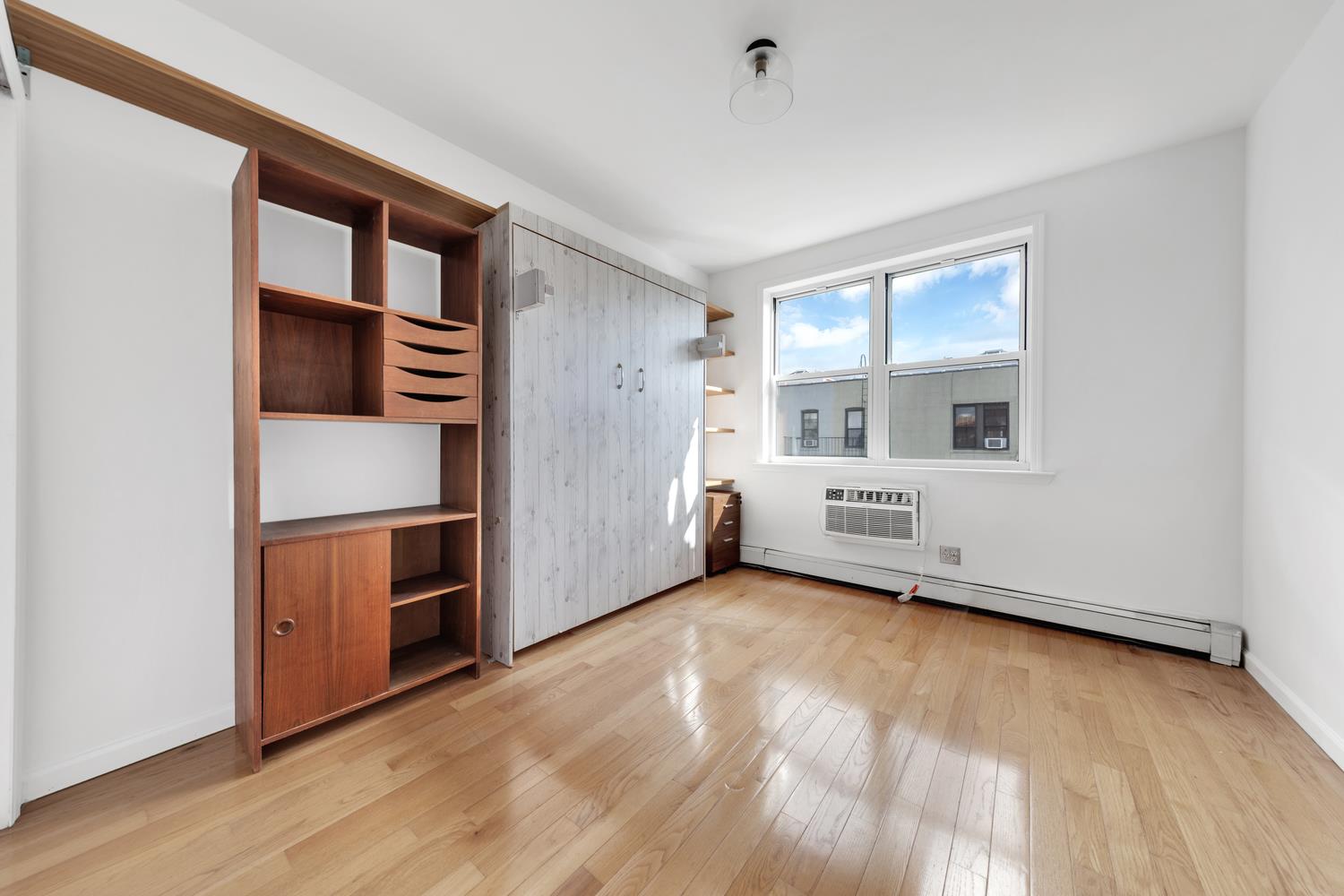 30-63 32nd Street, Unit 3B Queens, NY 11102 - Photo 8 of 12 a view of an empty room with kitchen and a window