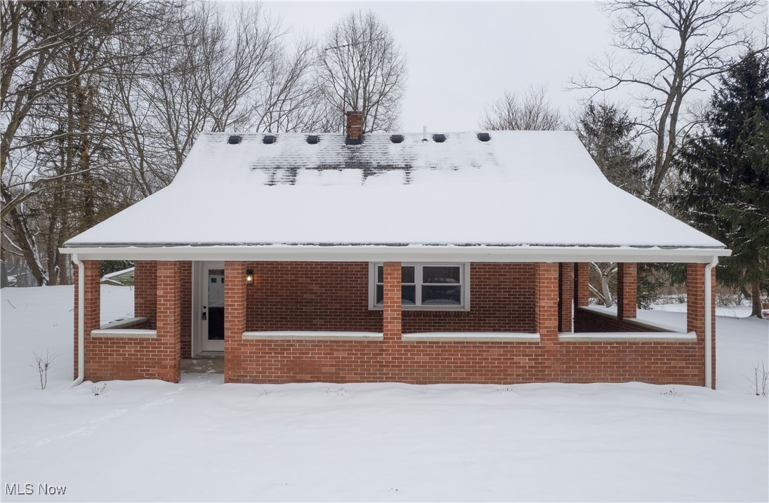 View of front of house featuring a chimney and brick siding