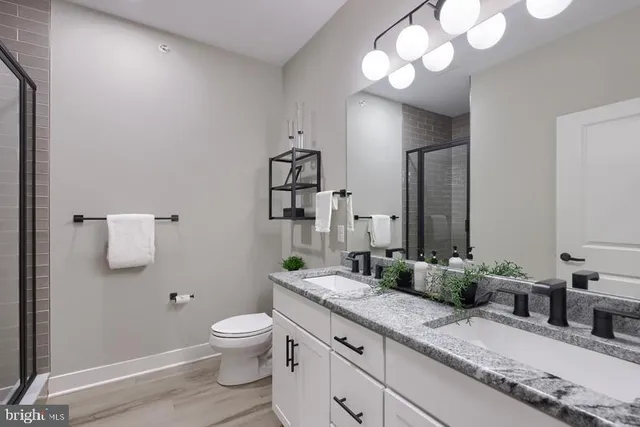 a bathroom with a granite countertop toilet a sink and a mirror