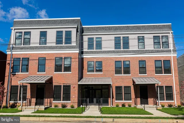 a front view of a brick building and yard with large windows