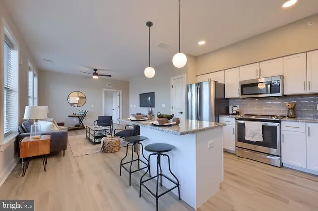 a very nice looking living room with stainless steel appliances furniture a rug and a large window