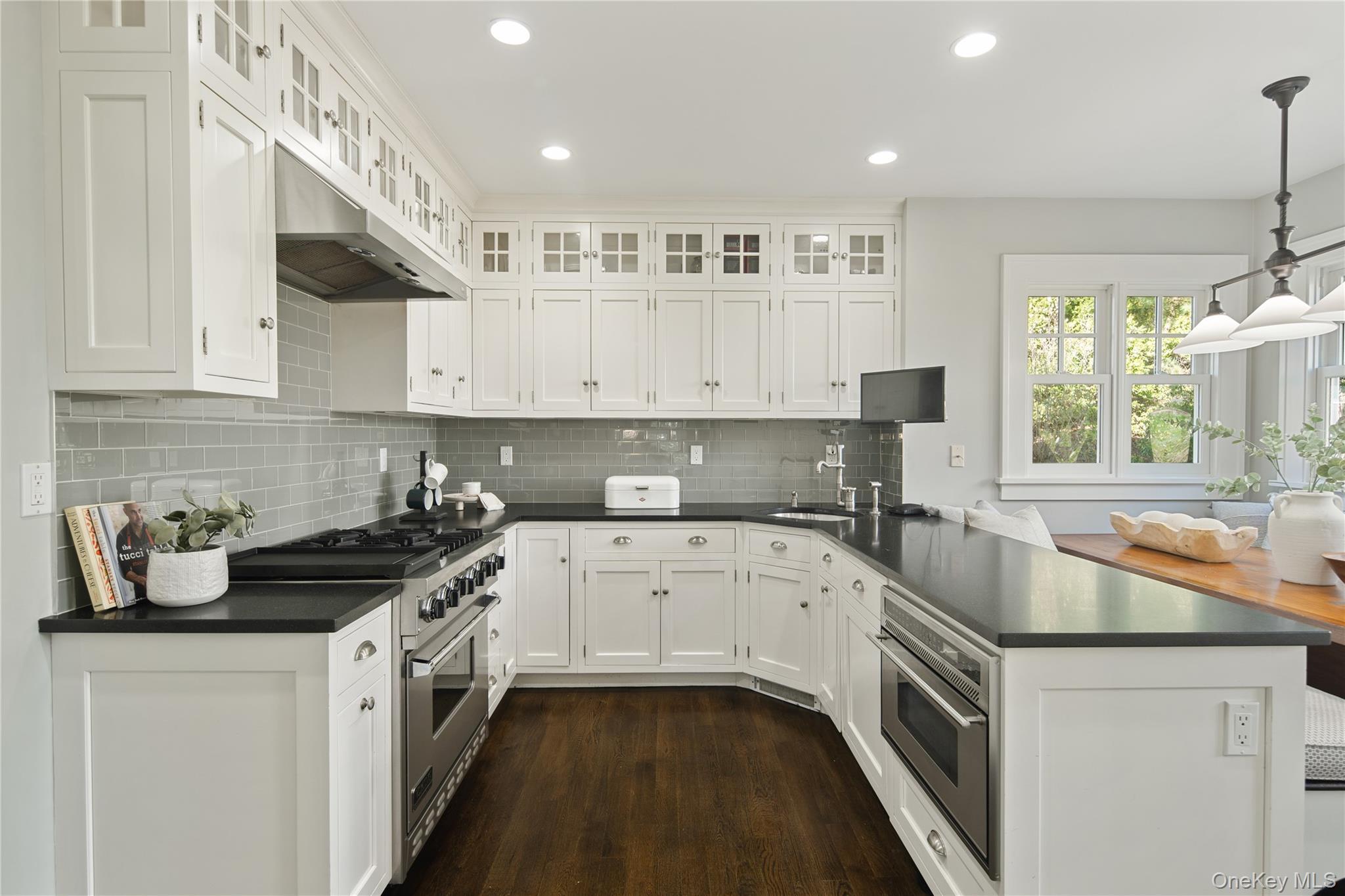14 Aldridge Road Chappaqua, NY 10514 - Photo 19 of 38 Eat-in kitchen with white inset style recessed panel cabinetry up to ceiling, glass tile backsplash, honed Absolut granite counters, large peninsula with storage and microwave below, SS appliances, Viking dual fuel range with convection oven, Subzero refrigerator with integral door panels, wall of floor to ceiling pantry storage,