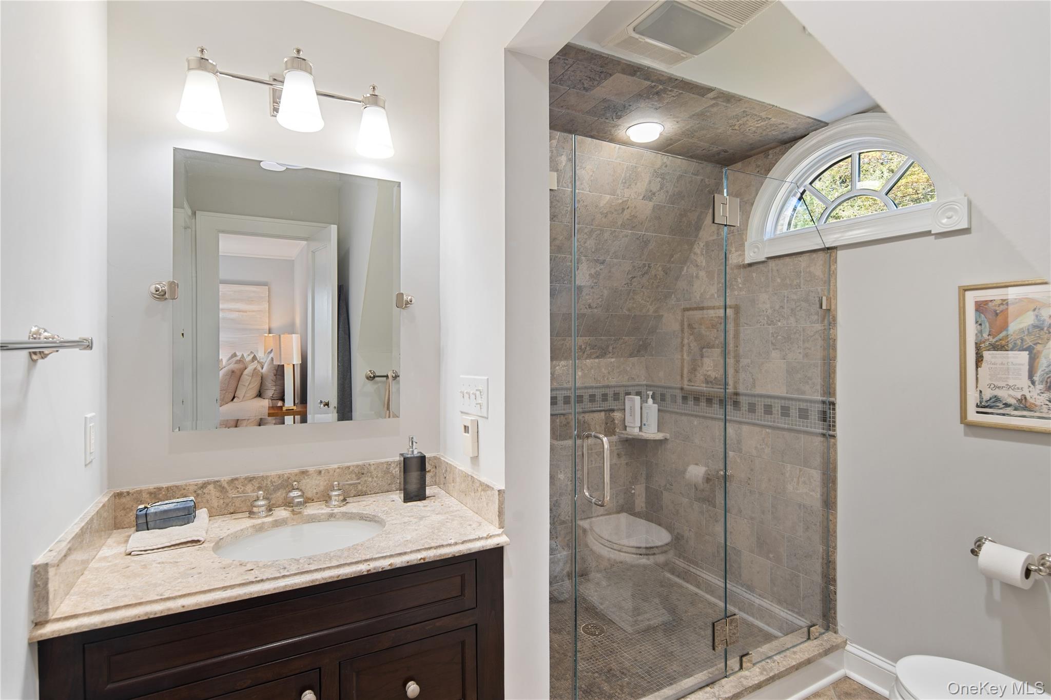 14 Aldridge Road Chappaqua, NY 10514 - Photo 27 of 38 En-suite full bath features storage vanity with granite counter and undermount sink, marble shower with frameless glass enclosure and wall mounted and hand held shower heads, radiant heated floor, wall sconce, beveled pivot mirror, Kohler fixtures, eyebrow window
