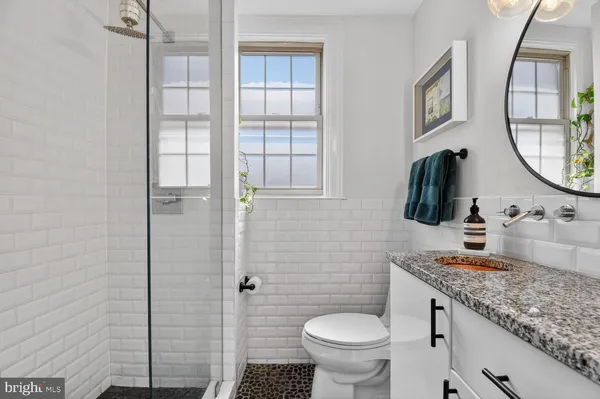 a bathroom with a granite countertop toilet sink and mirror