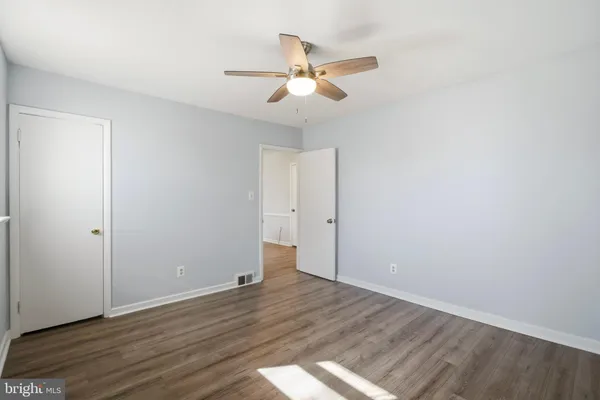 an empty room with wooden floor and ceiling fan