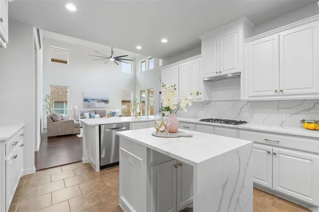a kitchen with a sink a stove top oven and white cabinets