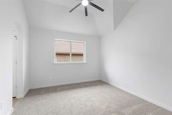 an empty room with a ceiling fan and carpet