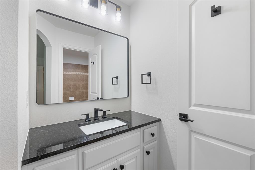 11984 Del Rio Drive Frisco, TX 75035 - Photo 35 of 38 a bathroom with a granite countertop sink and a mirror